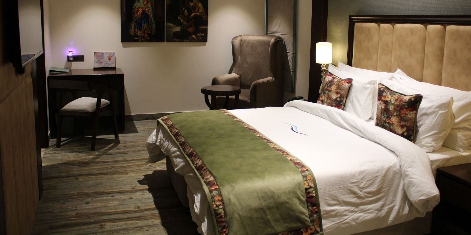 Side view of a bedroom featuring a working table, a chair, and portraits adorning the wall at BluSalzz Residence, Amritsar